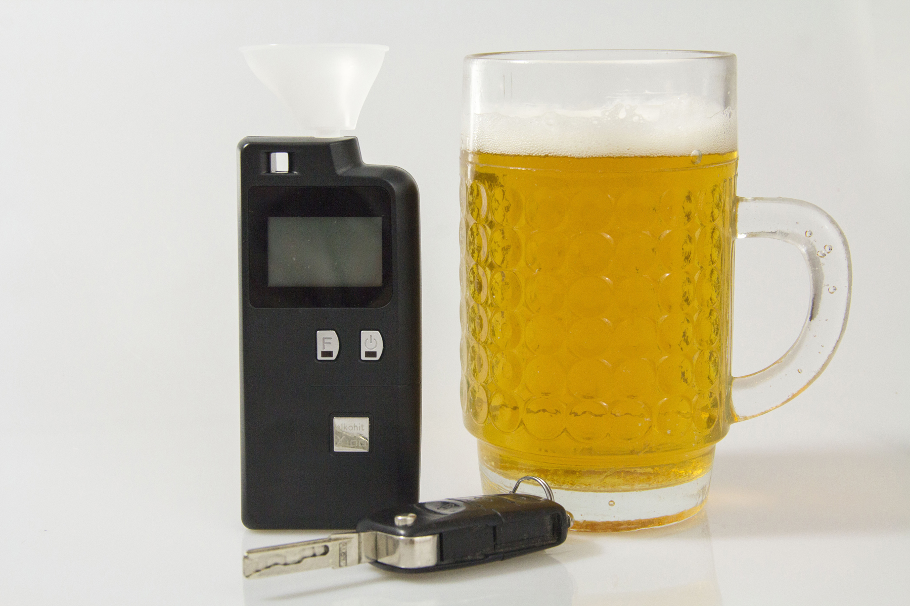 A breathalyser on a table next to a pint of beer and car keys