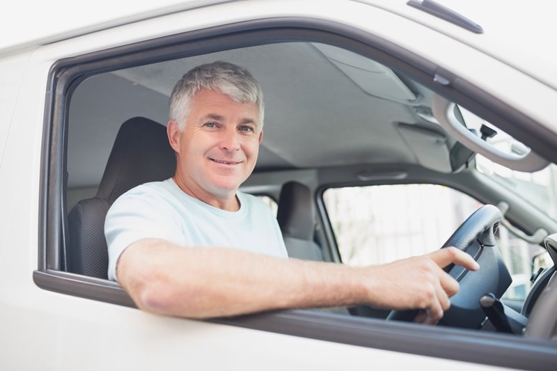 Man driving silver van with smile on his face