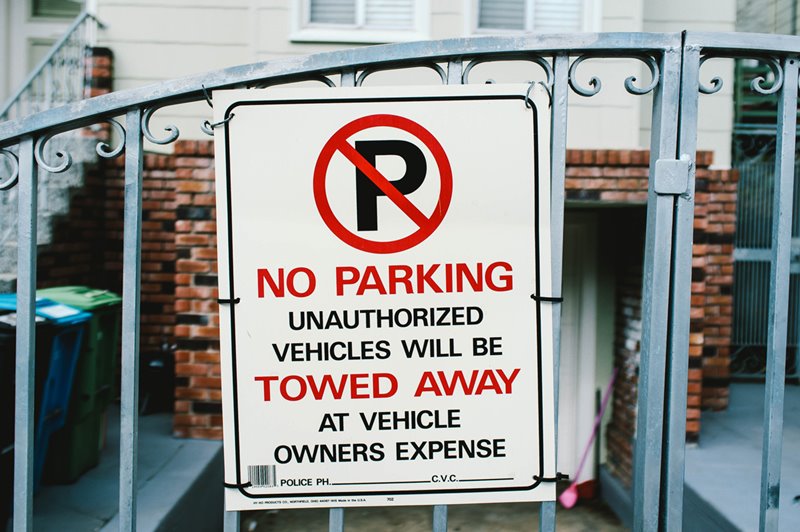 A private sign indicating no parking is allowed attached to the front gate of a house