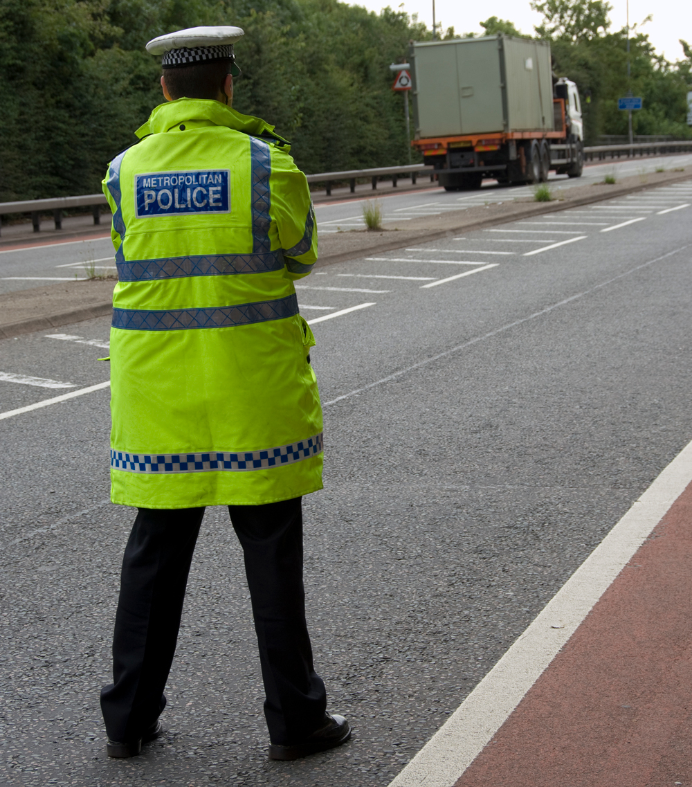 A police officer standing at a raodside watching traffic