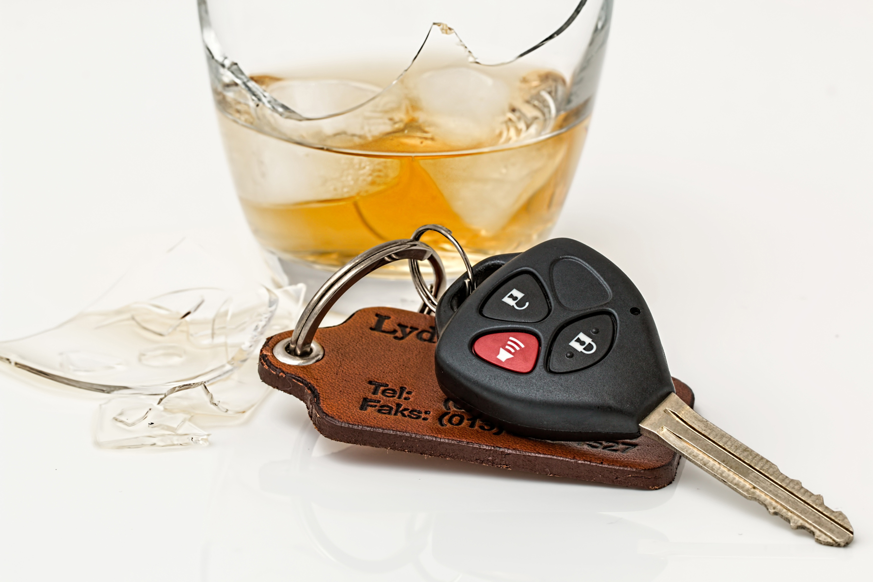 A glass of alcohol next to a pair of car keys