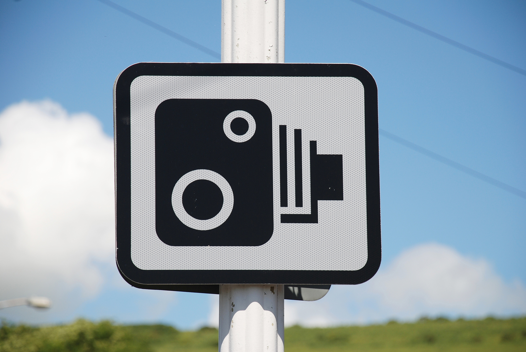 A sign next to a road depicting a speed camera