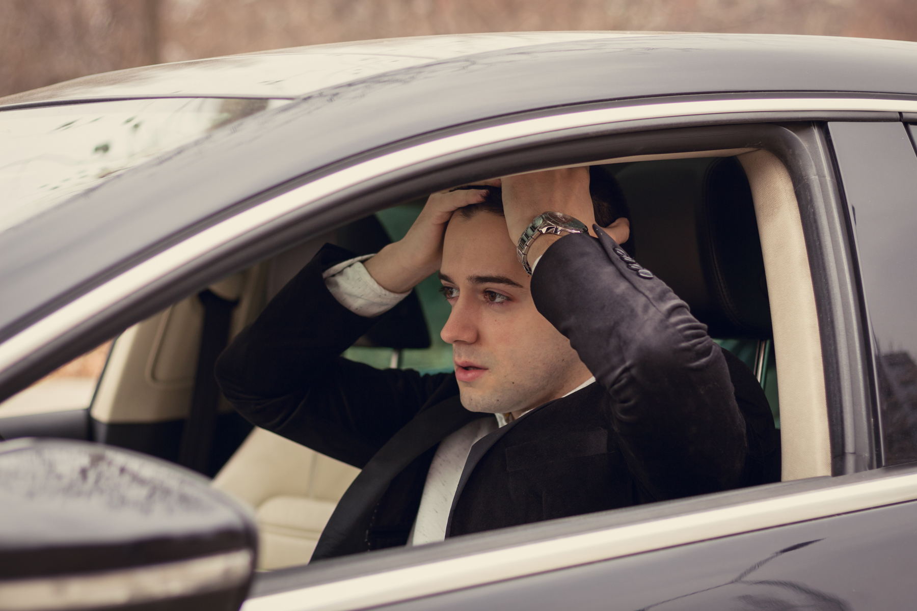 A man sitting in his car with his hands on his head after being pulled over